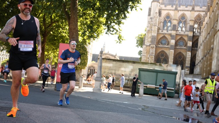 A picture of myself (Luc Shelton) running past the Palace of Westminster. There is someone to my left. I am wearing a SpecialEffect athletic jersey.